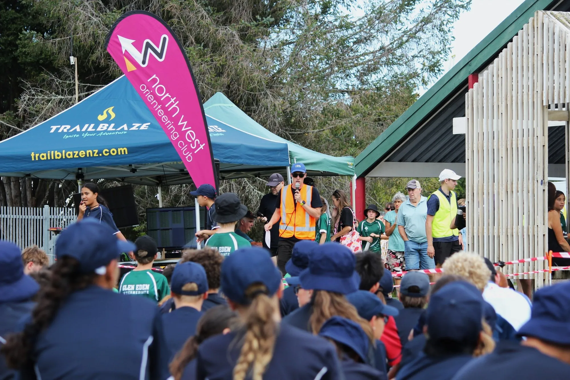 The TrailBlaze gazebo and a club flag over the assembly area at a Sprint Series event, with school groups waiting for the start